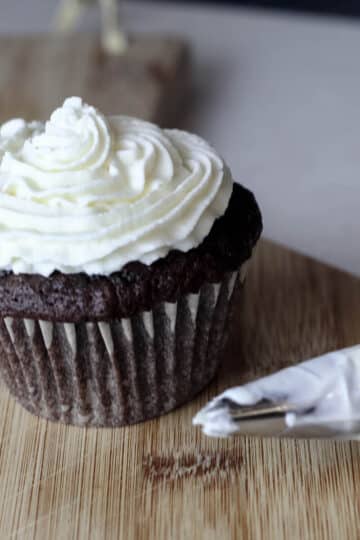 A swirl of marshmallow whipped cream frosting on top of a chocolate cupcake.
