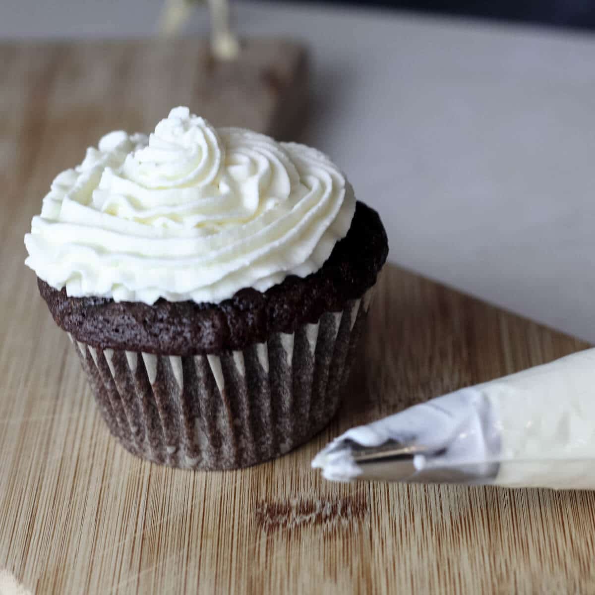 A swirl of marshmallow whipped cream frosting on top of a chocolate cupcake.