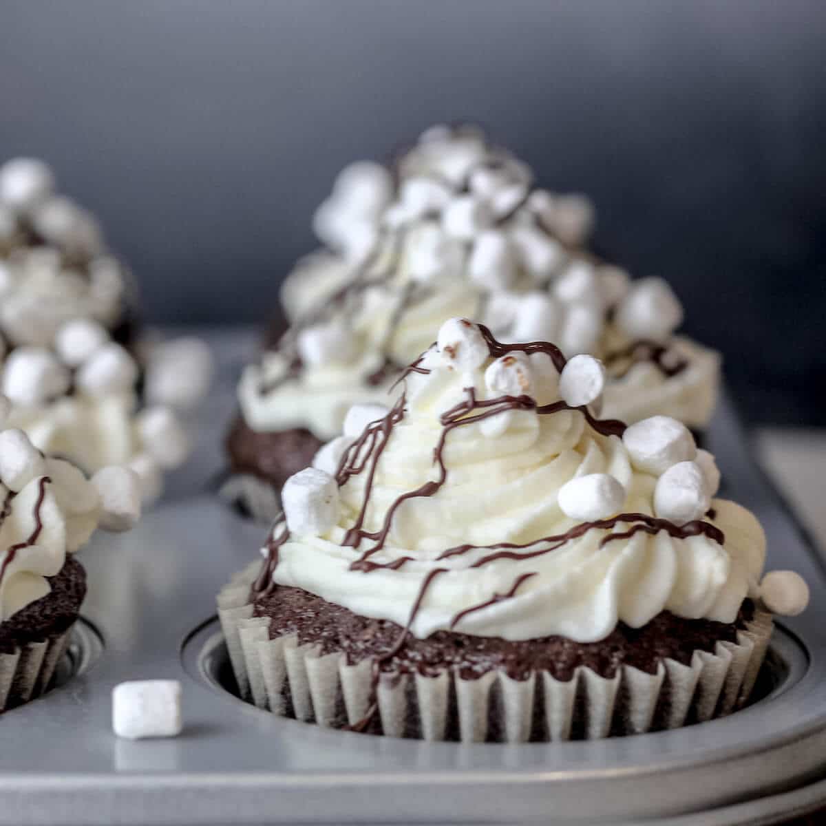 s'mores cupcakes with marshmallow creme frosting in a cupcake tin