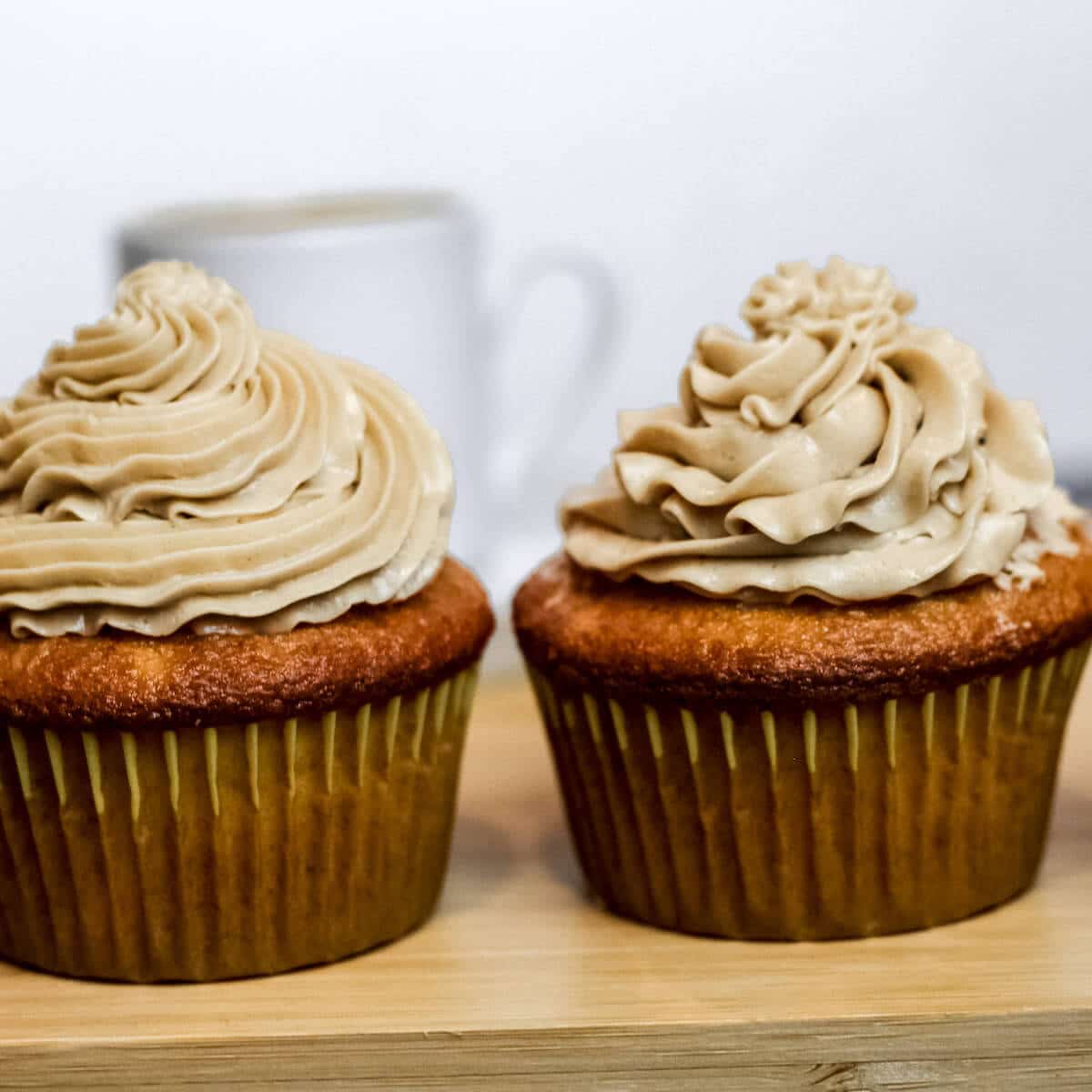 two cupcakes side by side with espresso frosting on top, with different techniques of cupcake swirl applied.